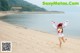 A woman in a white and red outfit running on a beach.