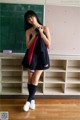 A woman in a school uniform standing in front of a blackboard.