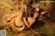 A naked woman laying on top of a pile of hay.