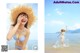 A woman in a blue bikini and a straw hat on the beach.