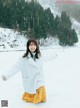 A woman in a white coat is standing in the snow.