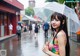 A woman standing in the rain holding an umbrella.