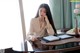 A woman sitting at a table with a laptop and a pen.