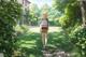 A woman walking down a path in a lush green garden.