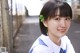 A young woman in a school uniform smiles at the camera.