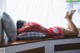 A woman laying on a window sill with her feet up on a pillow.