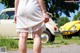 A woman in a white dress standing in front of a yellow car.