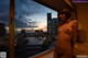 A naked woman standing in front of a window with a view of a city.