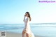 A woman standing on a beach next to the ocean.