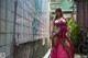 A woman in a pink dress standing next to a bike.