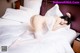 A woman laying on a bed in a white lingerie.